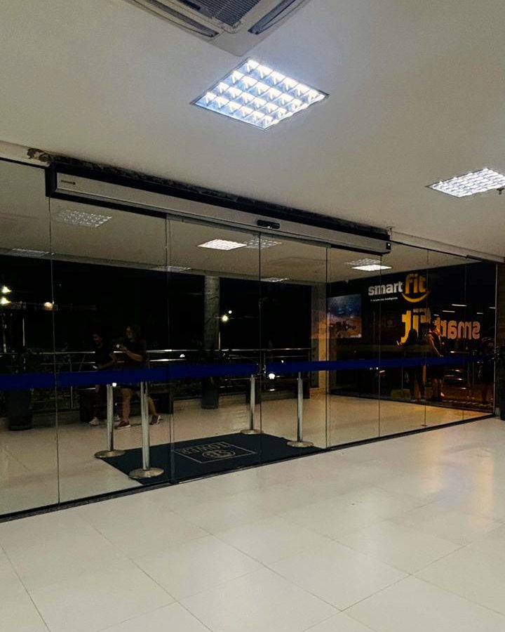 Porta automática de vidro na entrada de uma academia dentro de edifício comercial