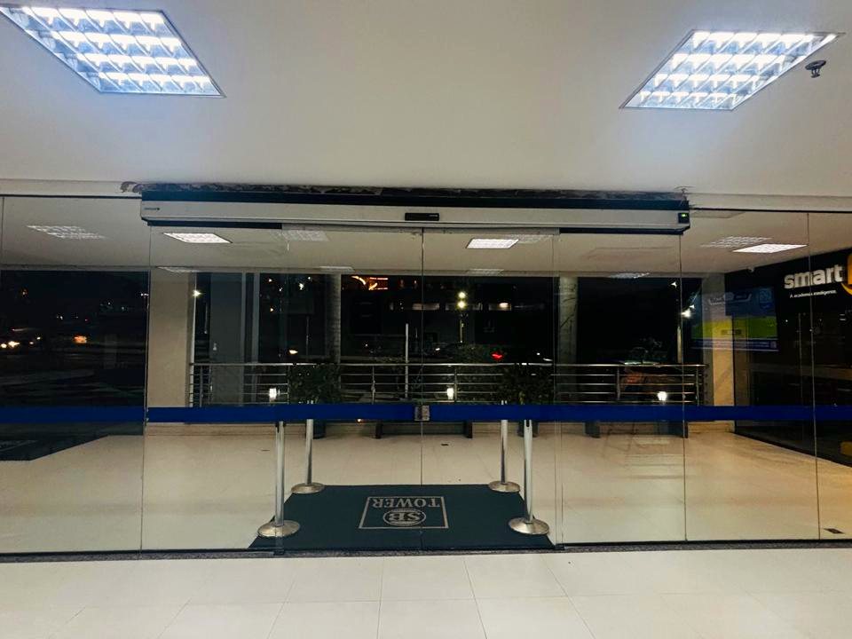 Hall interno com porta automática de vidro dando acesso a uma academia