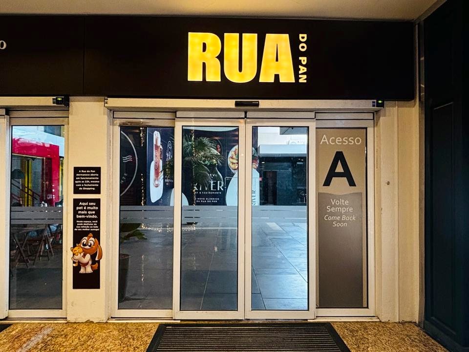 Porta automática de vidro na entrada iluminada de um comércio, à noite
