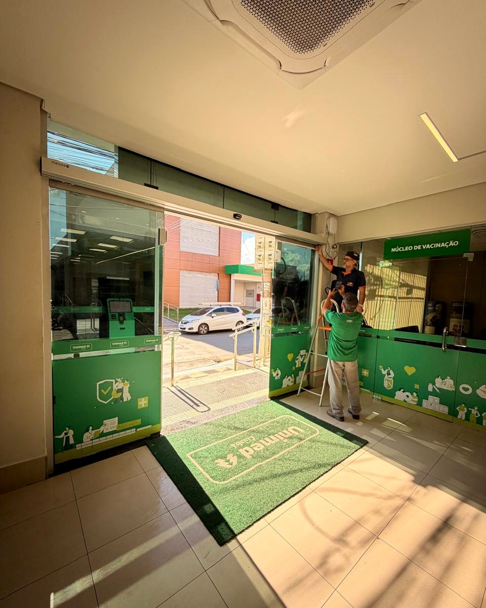 Equipe técnica instalando porta automática em unidade de saúde