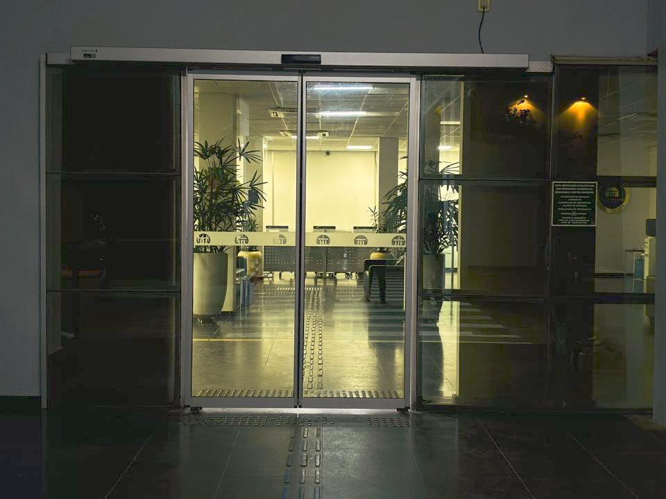 Hall de edifício iluminado à noite com porta automática de vidro